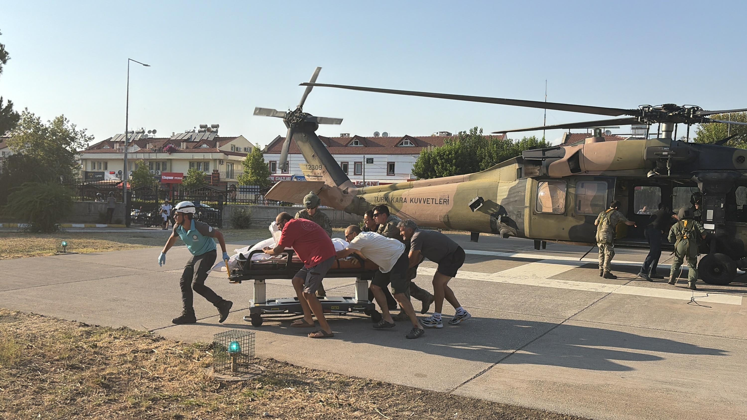 Helikopter yanında sedye taşıyan görevliler ve ekipler.