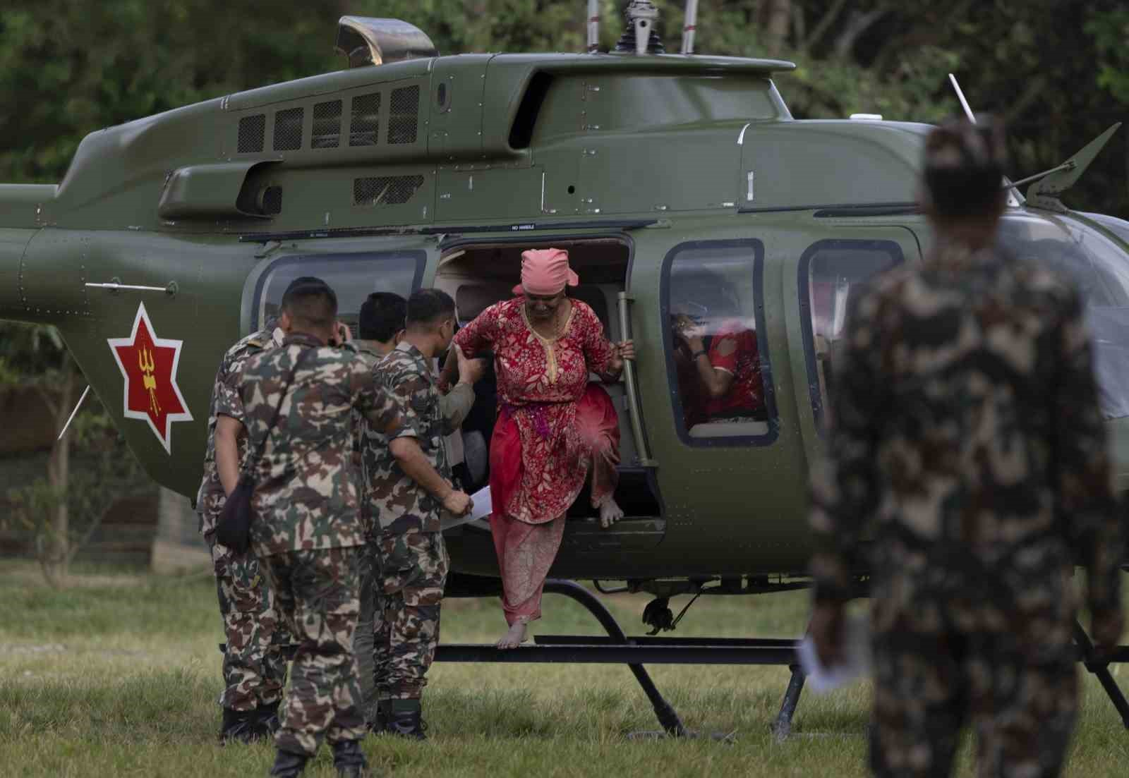 Nepal ordusuna ait helikopterden indirilen afetzedelere askerlerin yardım ettiği görüntü.
