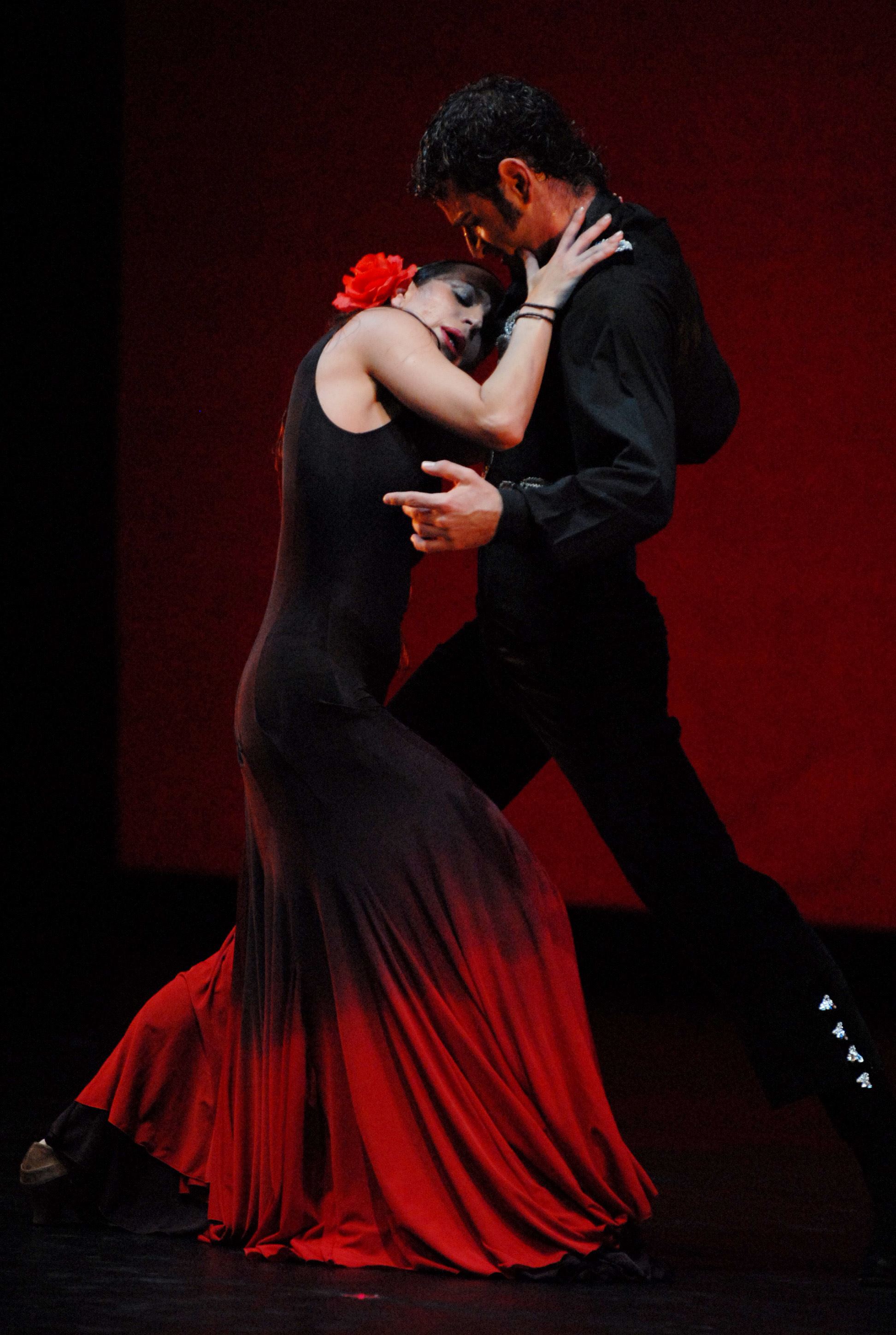 Deux artistes dansant devant un fond rouge sur la scène de Carmen.