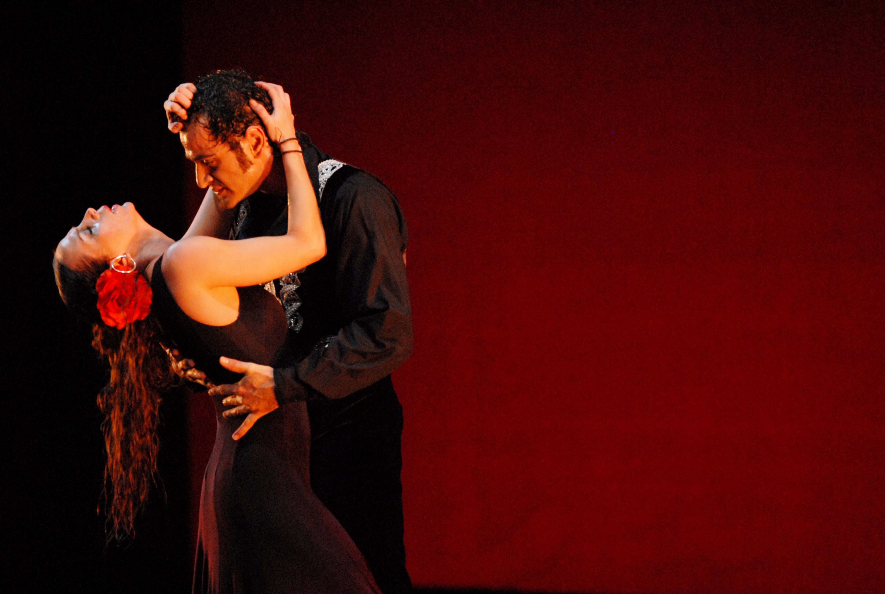 Une scène de danse dramatique devant un arrière-plan rouge.