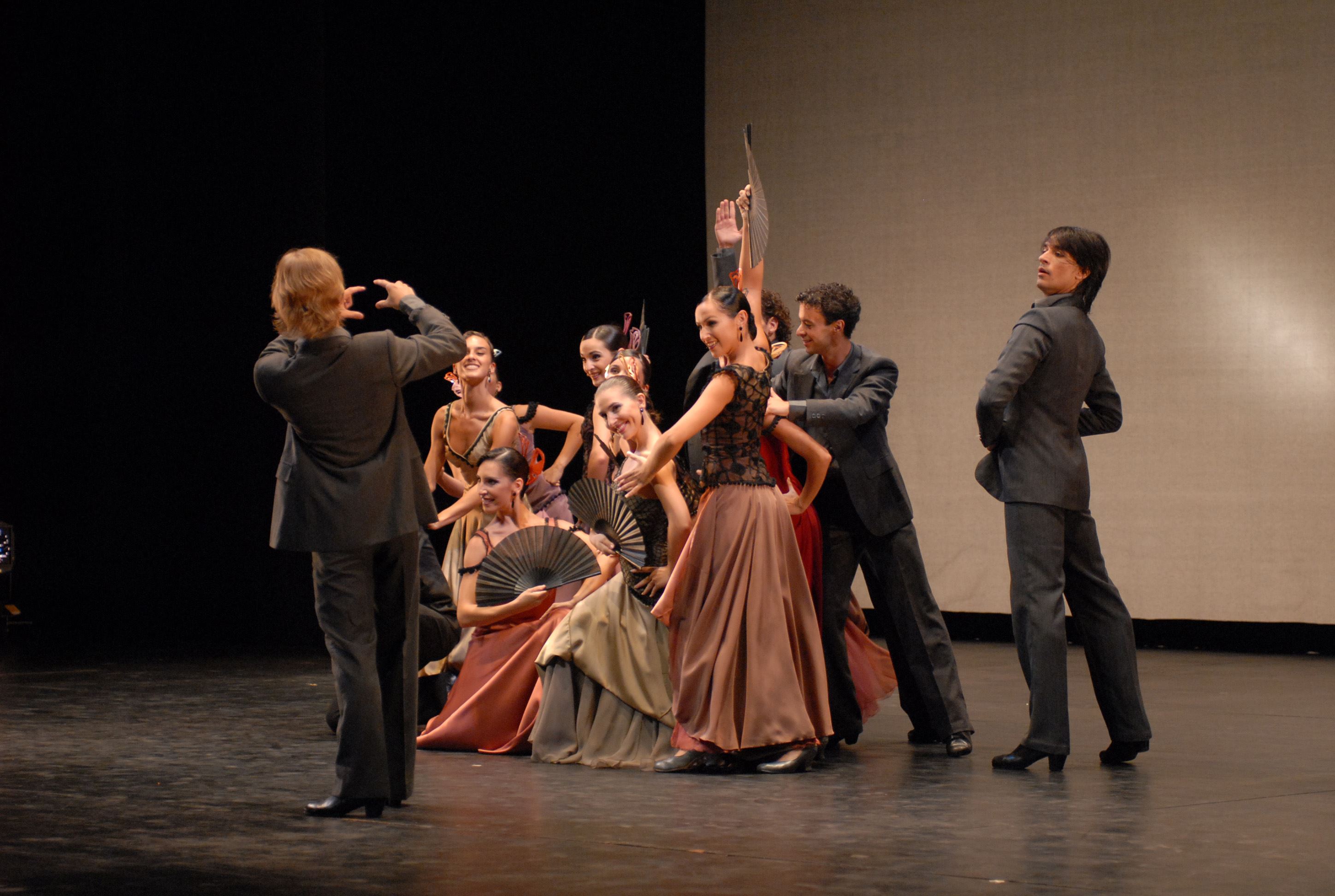 Vue d'une troupe composée de la directrice et des danseurs sur scène.