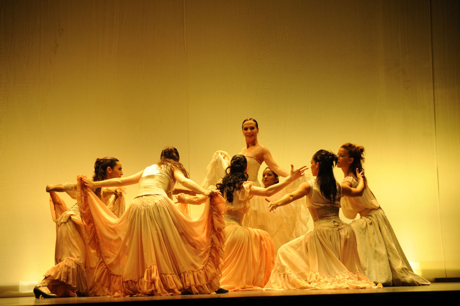 Aída Gómez et sa troupe sur scène sous une lumière jaune.