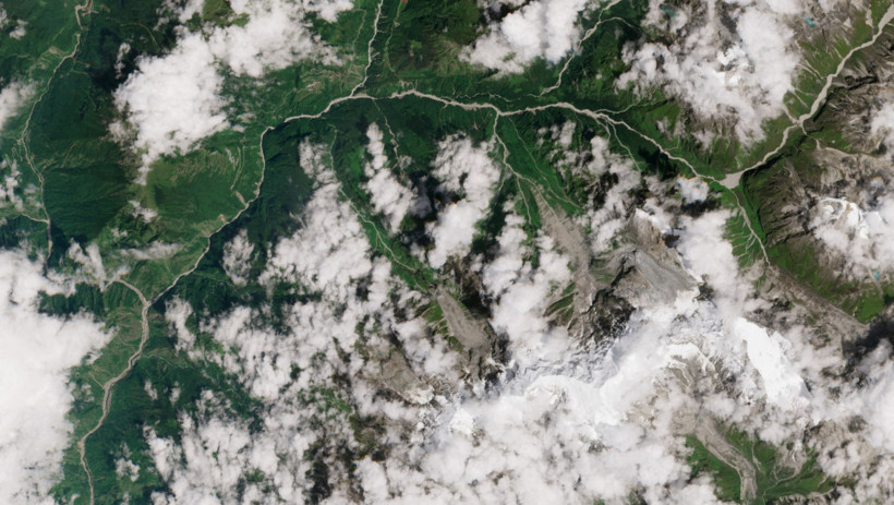 Satellite image showing a mountainous and forested region partially covered by clouds.