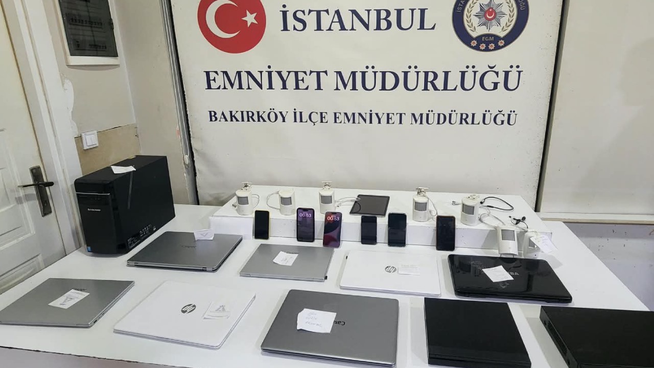 Bakırköy İlçe Emniyet Müdürlüğü’nde masa üzerine dizilmiş dijital cihazlar, telefonlar, bilgisayarlar ve gizli kamera düzenekleri.