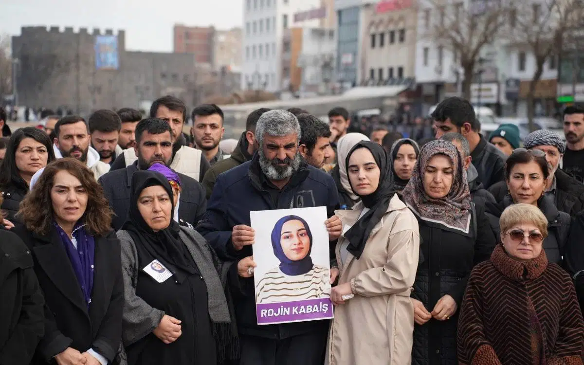 Rojin Kabaiş’in ailesi ve yakınları, üzerinde Rojin Kabaiş’in fotoğrafı bulunan bir afişle açıklama sırasında görülüyor.