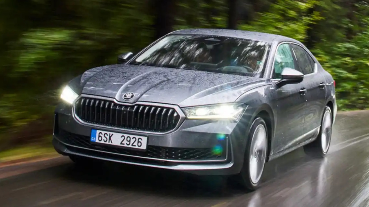 Skoda marka gri bir otomobilin yağışlı yolda ilerlediği görsel.