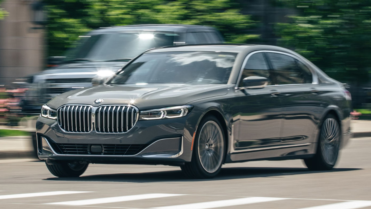 BMW marka gri bir sedan otomobilin şehir içinde ilerlediği görsel.