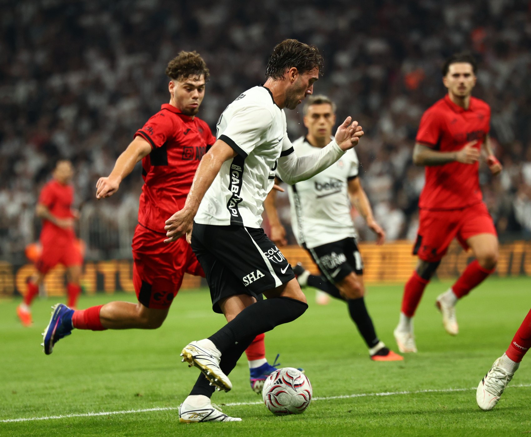 Beşiktaşlı bir futbolcunun Çorum FK oyuncularının baskısı altında topla ilerlediği maç anı.