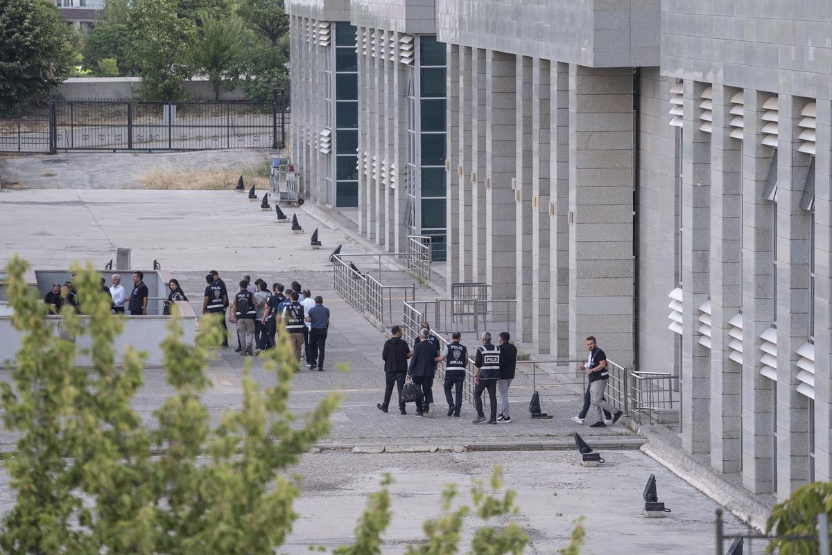Geniş bir kamu binası çevresinde polis ekipleri ve görevlilerin bulunduğu görüntü.