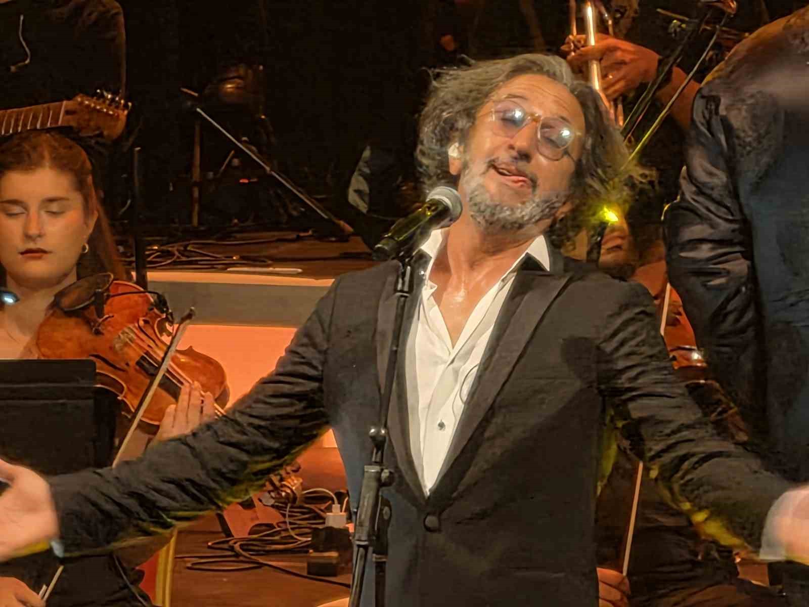 Fettah Can, konser sırasında mikrofon başında performans sergiliyor.