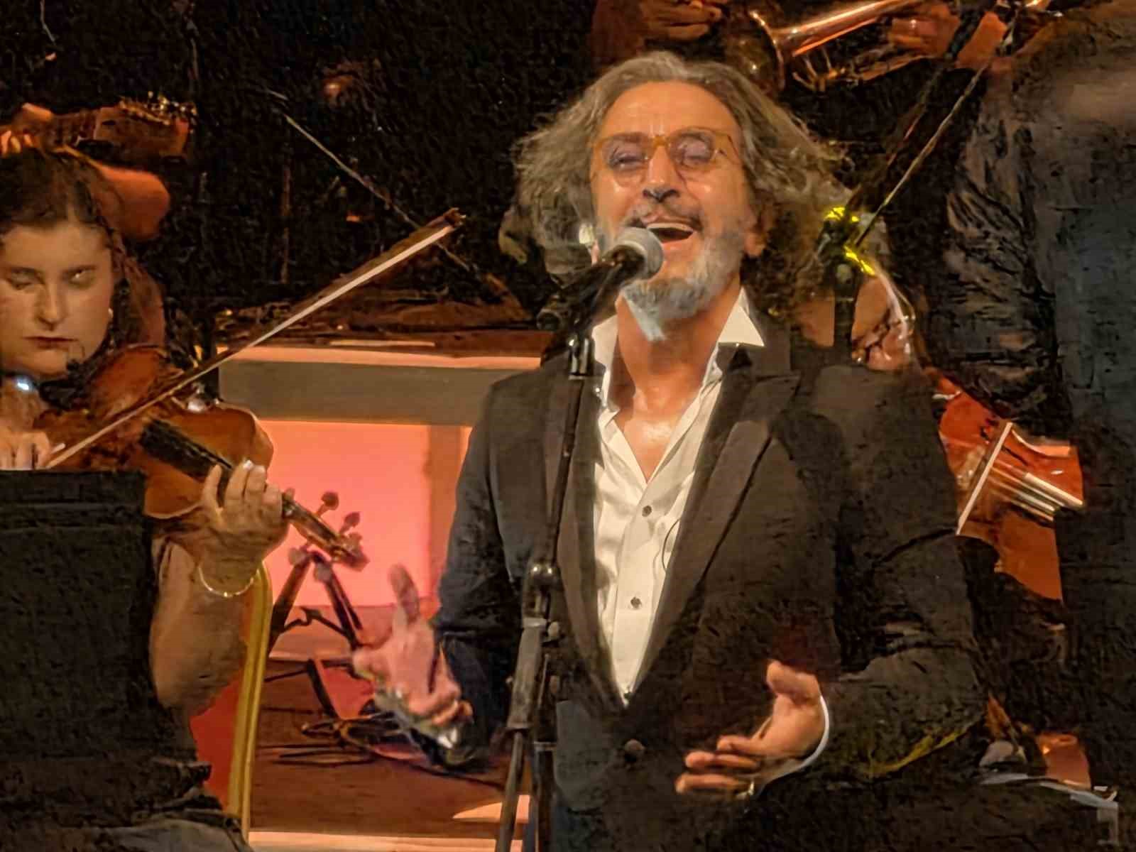 Fettah Can, sahnede orkestrayla birlikte şarkı söylerken görülüyor.