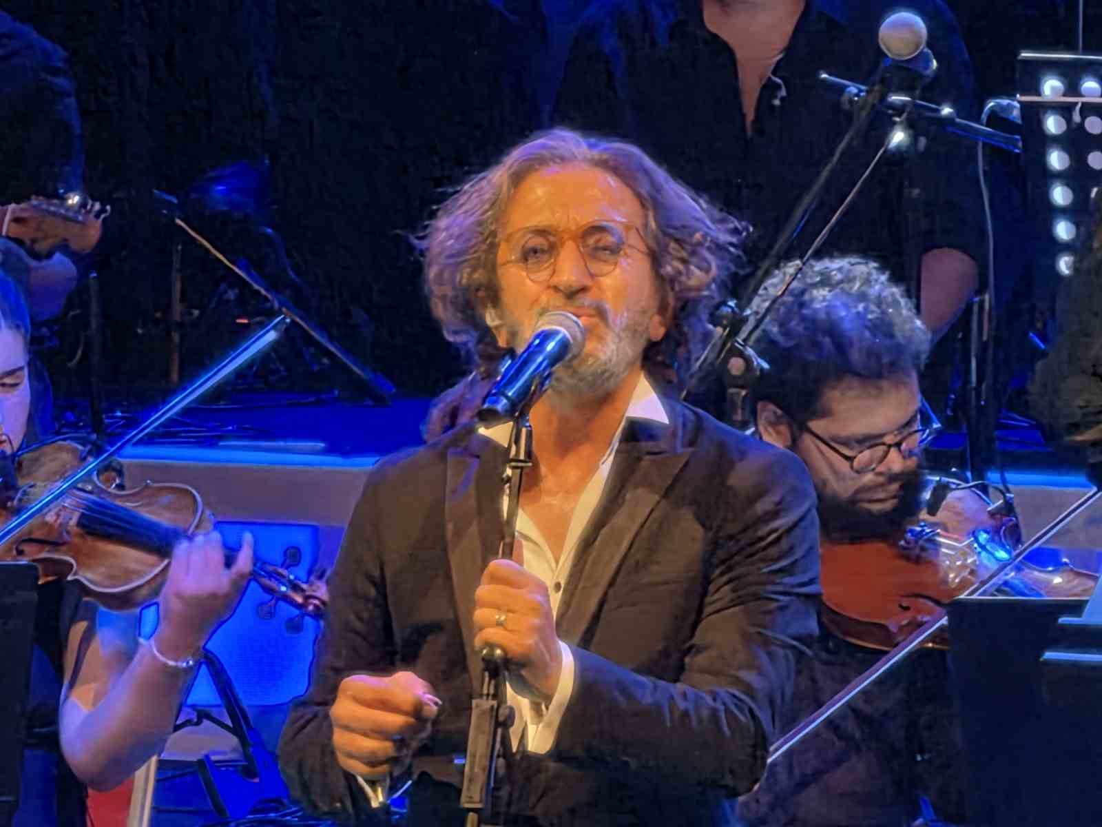 Fettah Can, mikrofon başında yakın planda sahnede görülüyor.
