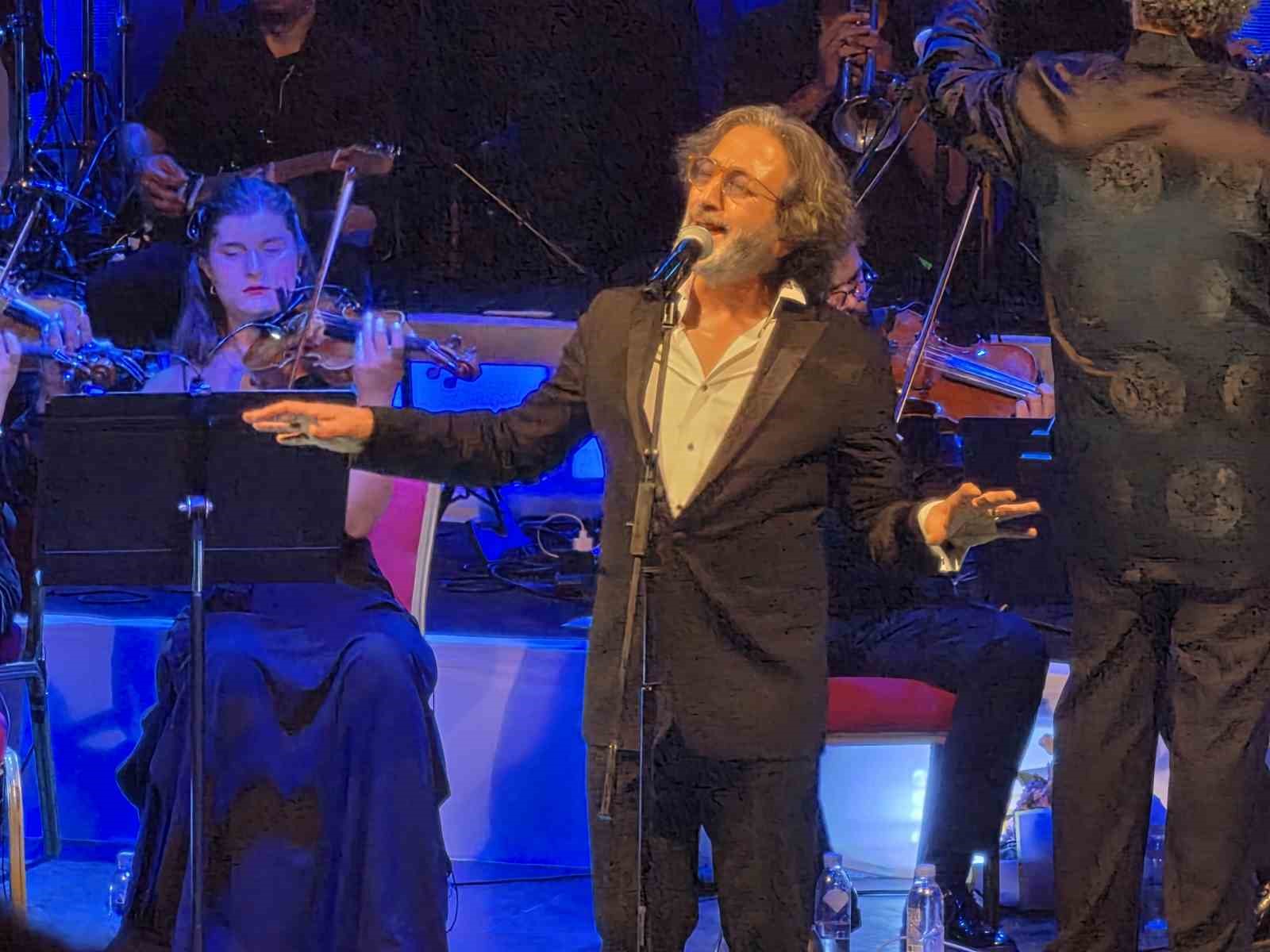 Fettah Can, sahnede kollarını açarak performans sergiliyor.