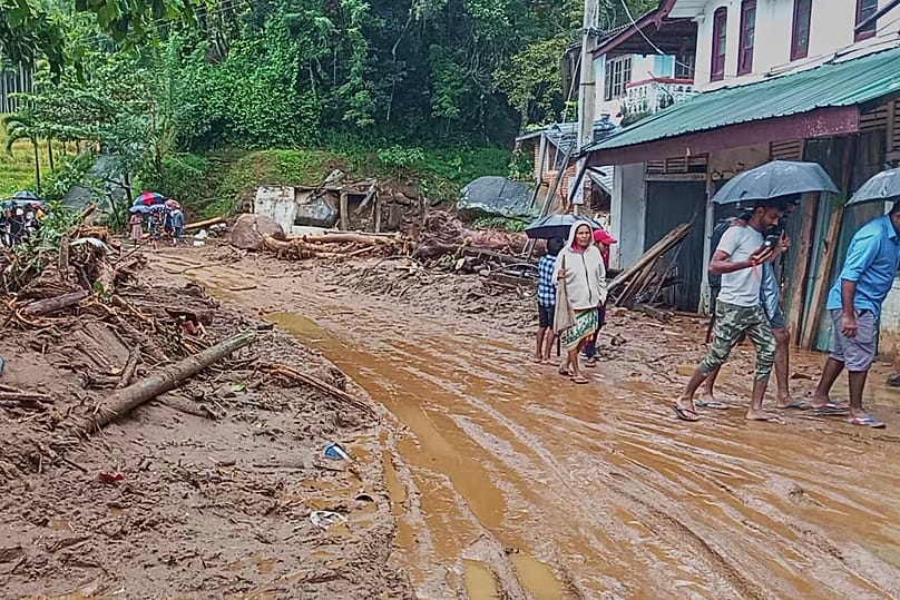 Sri Lanka’nın Nawalapitiya bölgesinde çamurla kaplanan bir yolda yürüyen insanlar.
