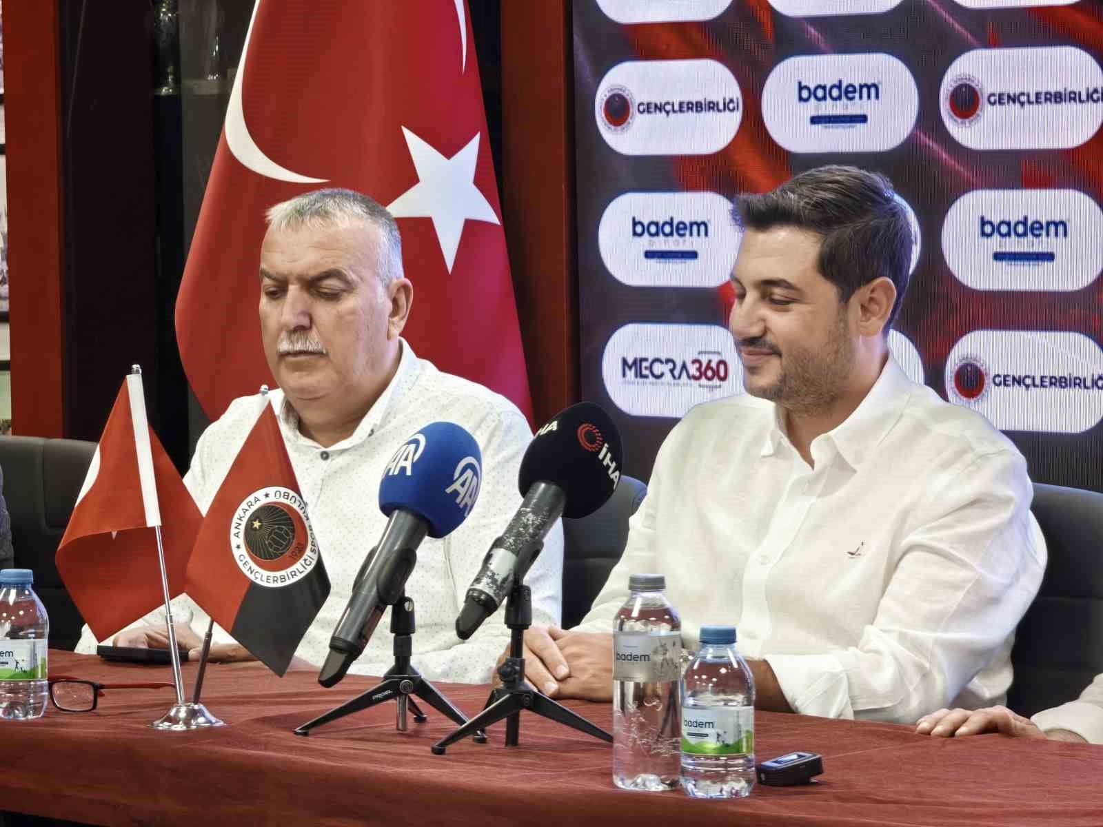 Gençlerbirliği bayrağı, mikrofonlar ve sponsor panosu önünde tören katılımcıları.