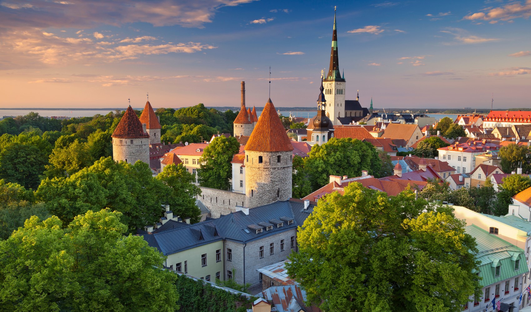 Tallinn’in tarihi şehir merkezi, kuleleri ve yeşil alanlarıyla gün batımında görülüyor.