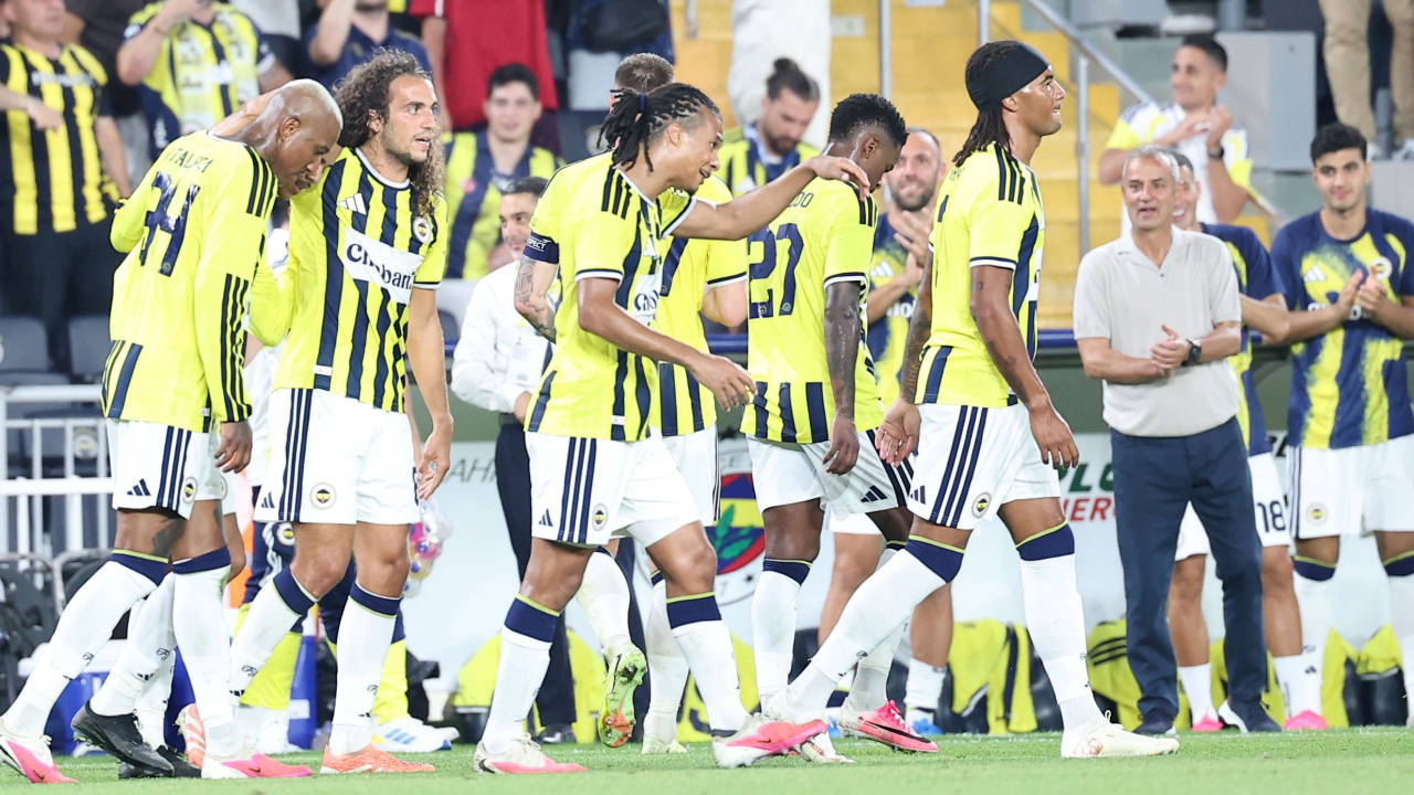Fenerbahçeli futbolcuların sahada taraftarların önünde yürüdüğü görüntü.
