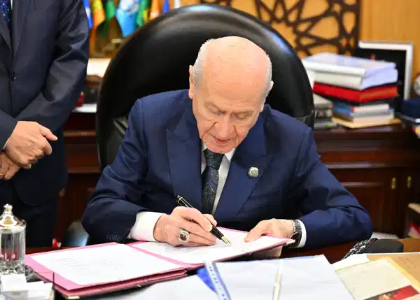 MHP Genel Başkanı Devlet Bahçeli, makamında bir dosyayı imzalarken görülüyor.