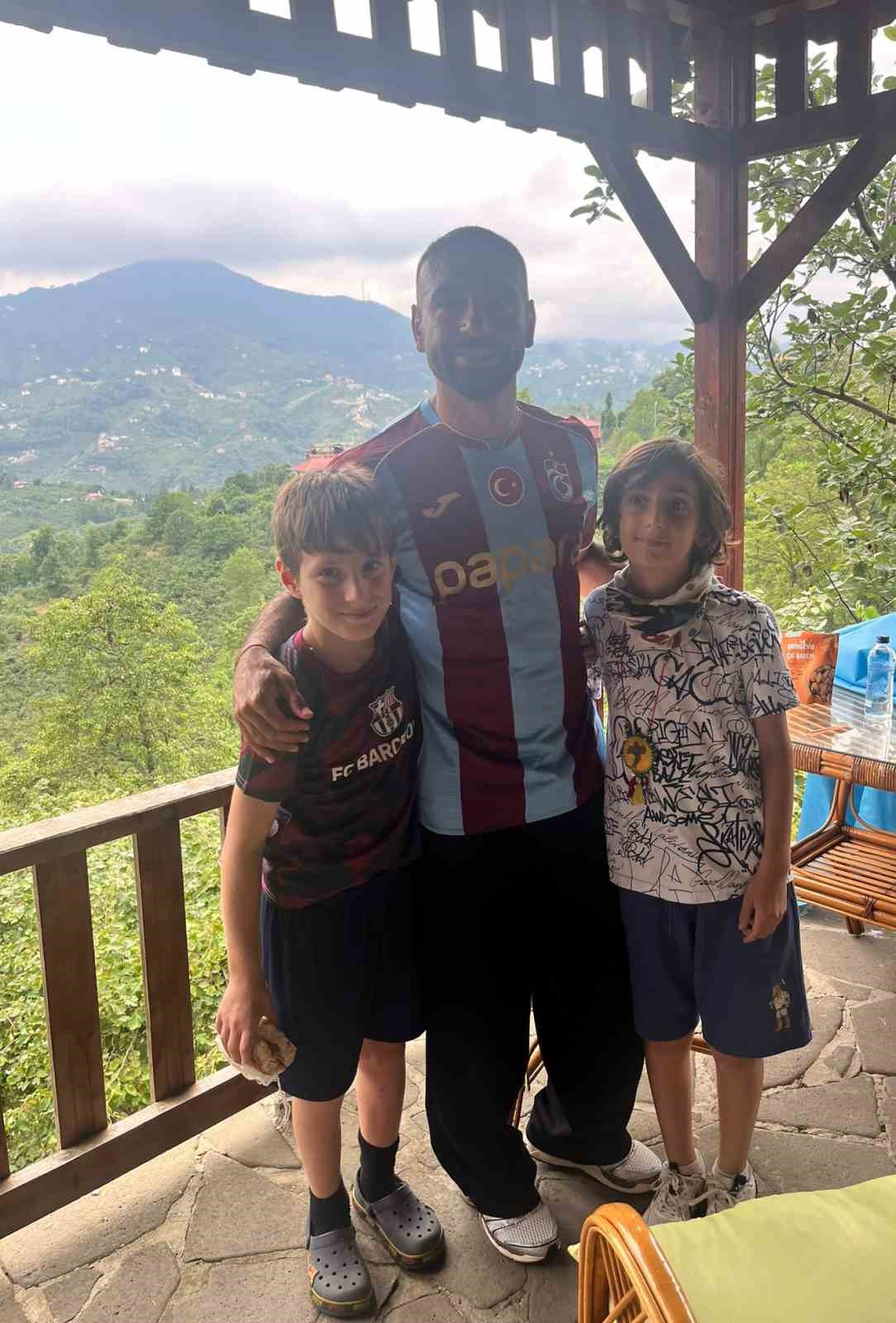 Muhammed Salah, Trabzonspor formasıyla iki çocukla birlikte yeşil doğa manzarası önünde poz veriyor.