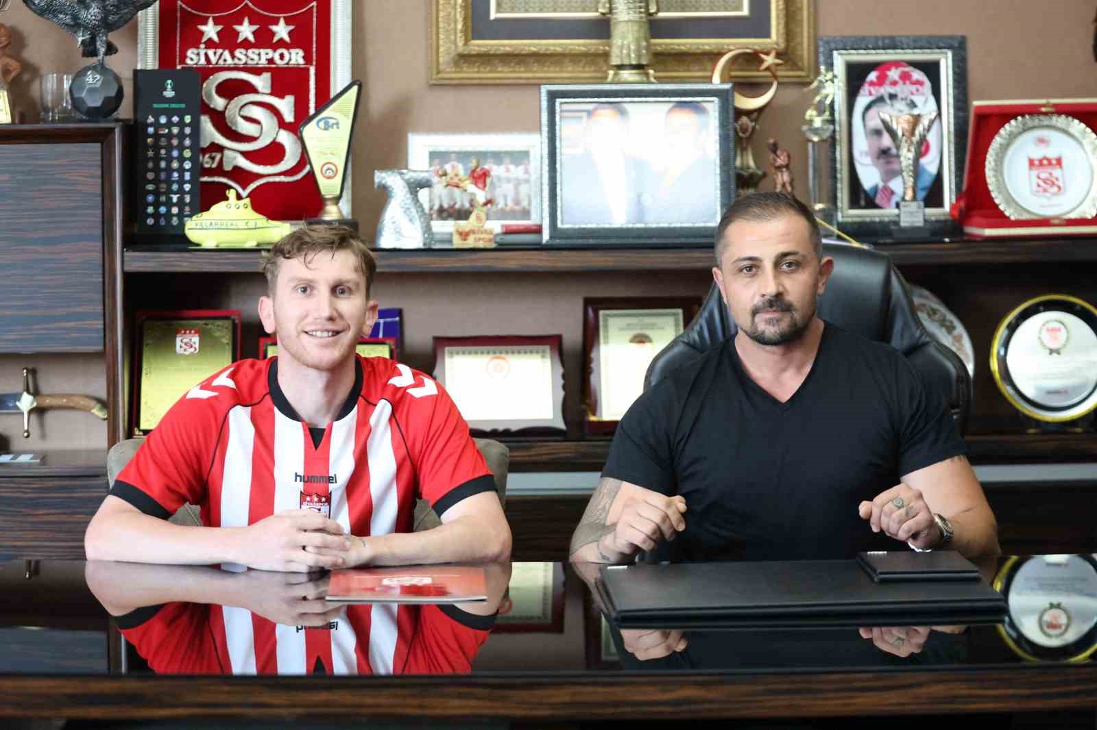 Sivasspor formasıyla imza törenine katılan futbolcu ve kulüp yetkilisi.