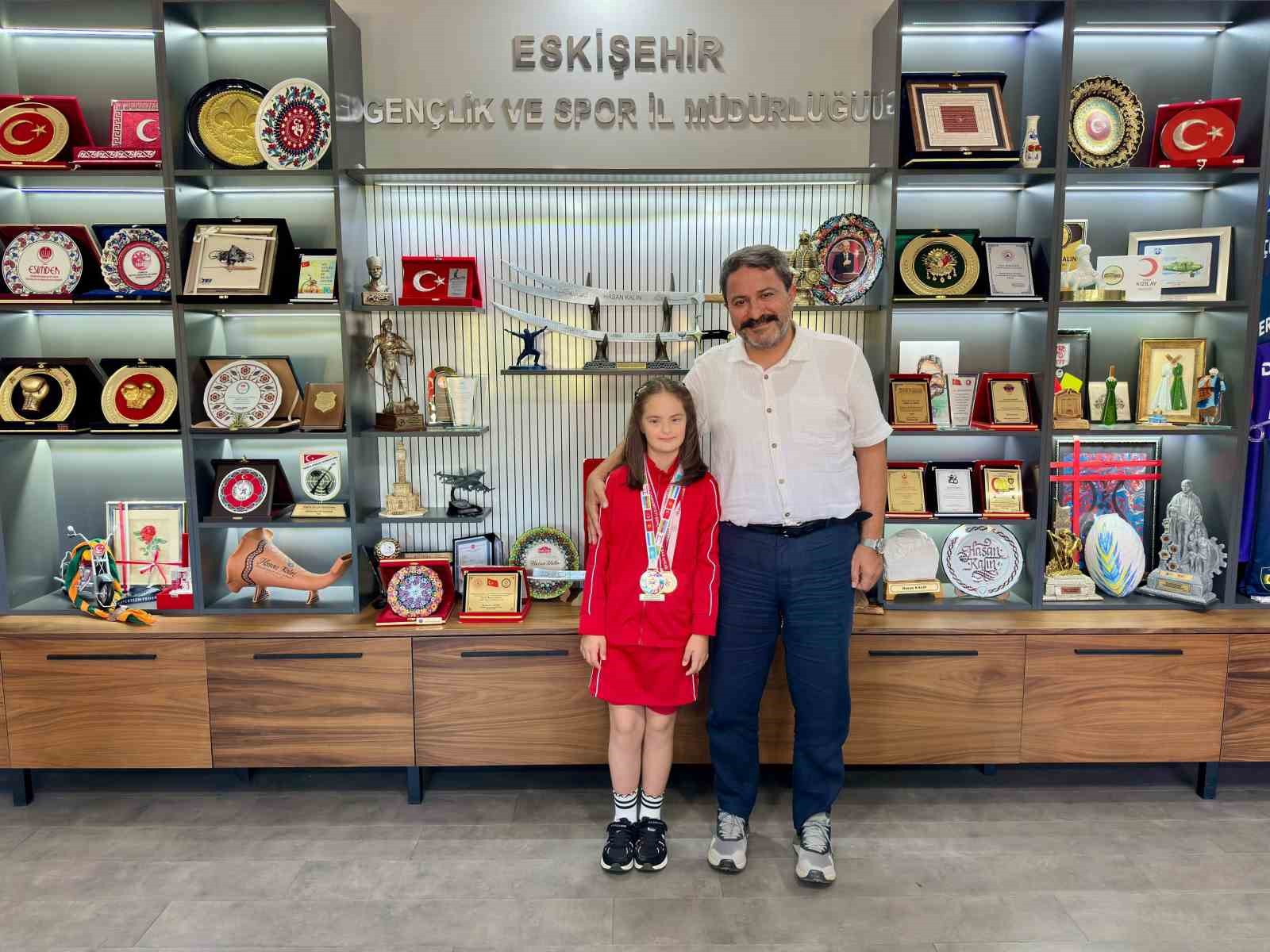 Elif Ertek ve Eskişehir Gençlik ve Spor İl Müdürü Hasan Kalın, müdürlükte madalyalarla birlikte poz veriyor.
