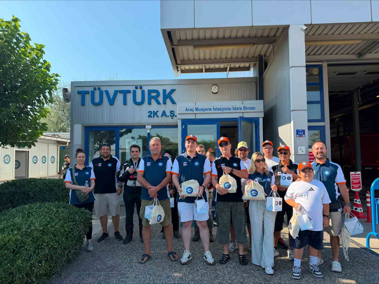 Anadolu Dostluk Rallisi katılımcıları TÜVTÜRK araç muayene istasyonu önünde hediyelerle birlikte görülüyor.