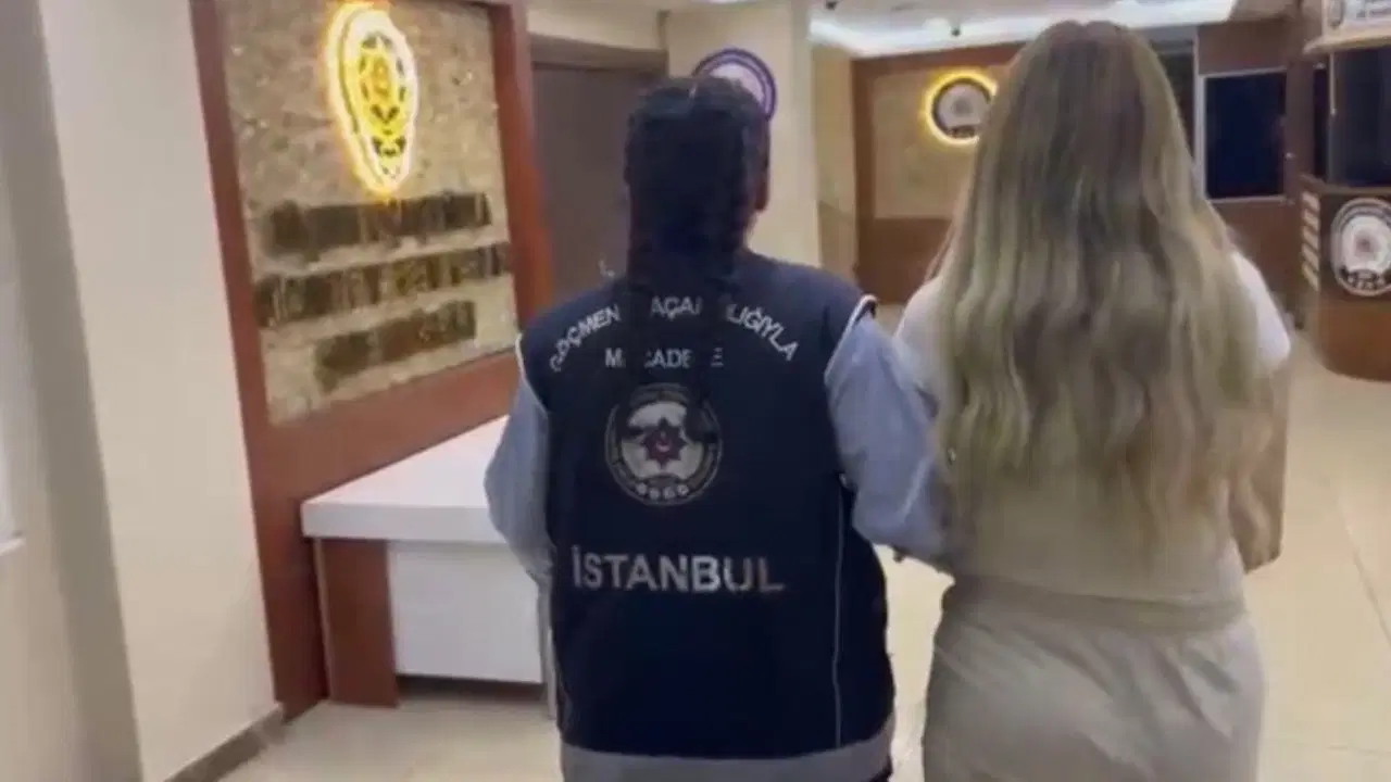 İstanbul Emniyeti görevlisi eşliğinde yürüyen kadın.