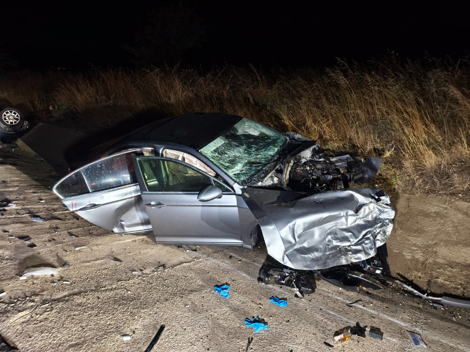 Ön kısmı ağır hasar alan otomobilin gece yol kenarında bulunduğu kaza yeri.