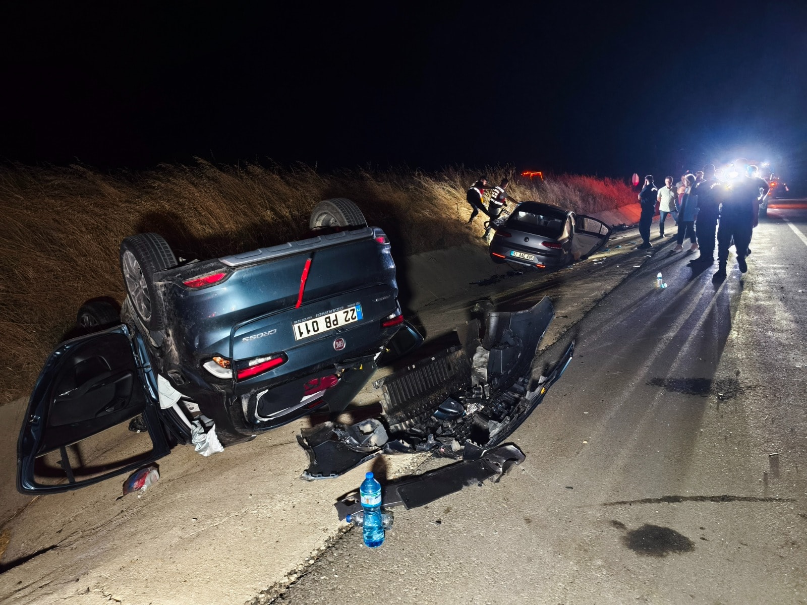 Kaza yerinde devrilen otomobil, hasarlı araçlar ve ekiplerin çalışması görülüyor.