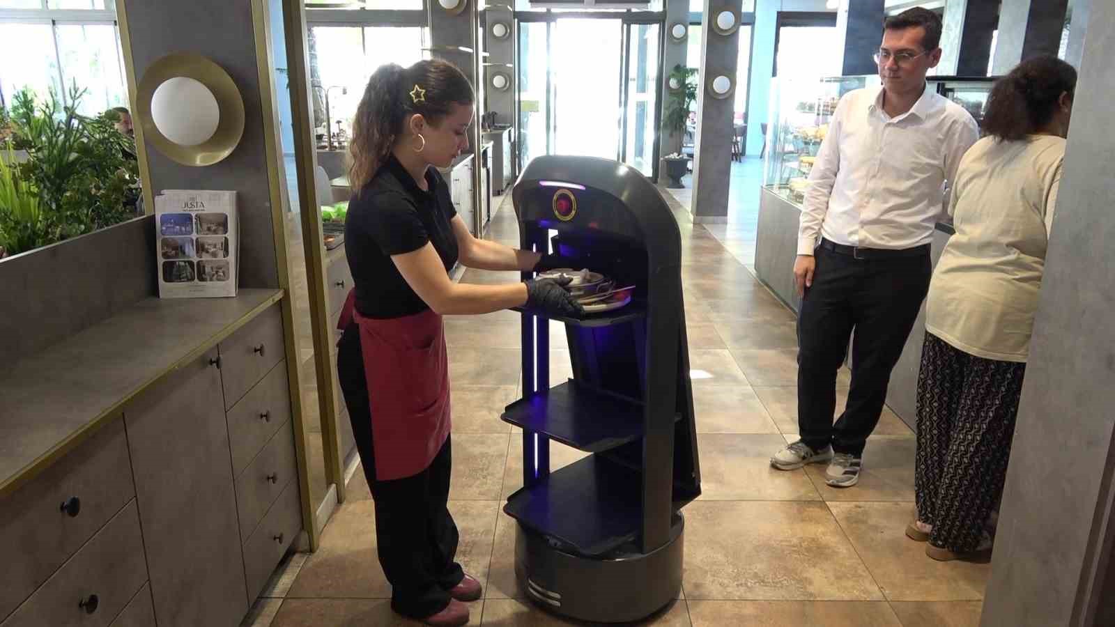 Bir restoran çalışanının Gayretli adlı servis robotuna servis ekipmanı yerleştirdiği an.