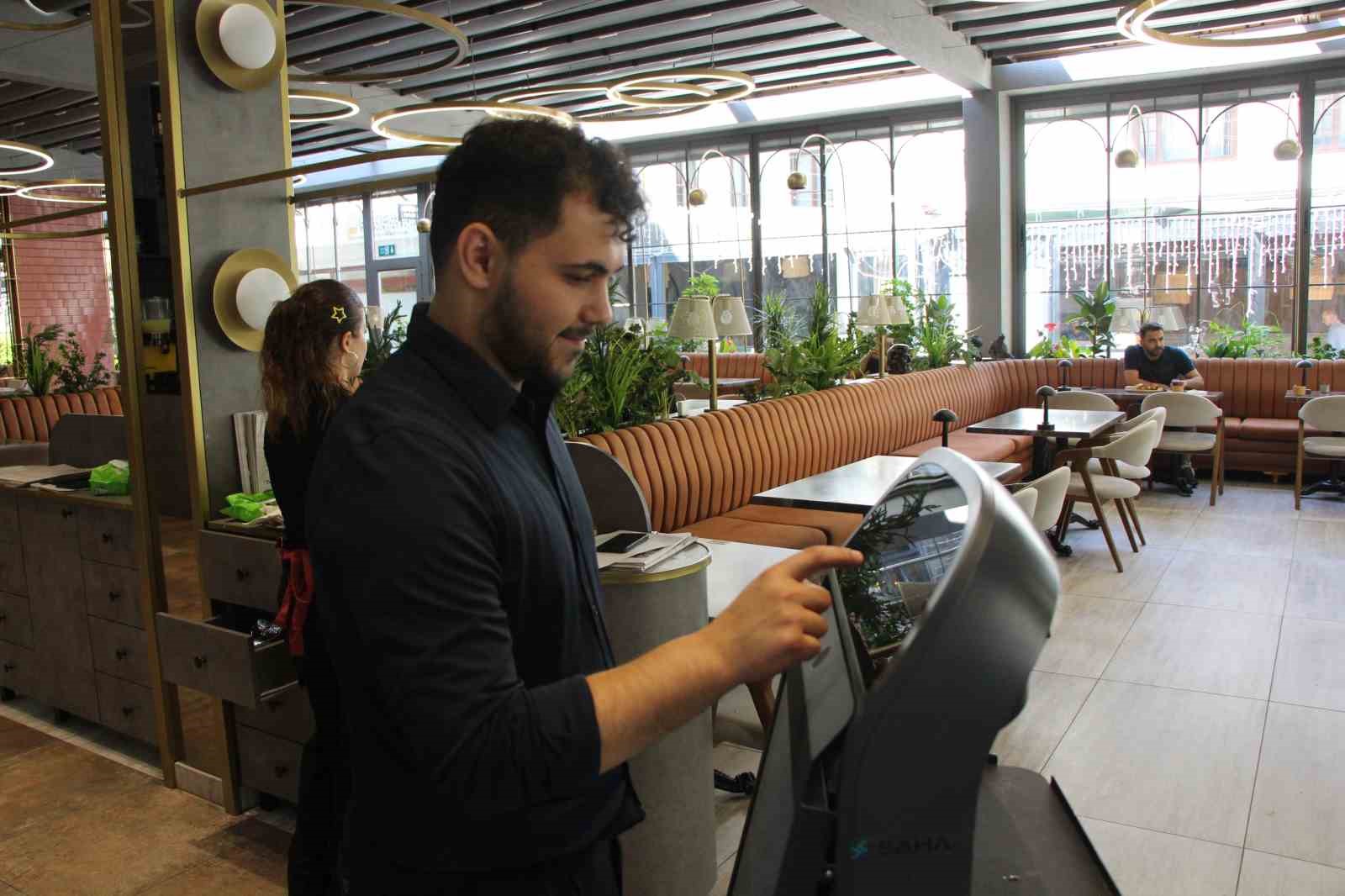Restoran içinde bir çalışanın Gayretli adlı robotun ekranını kontrol ettiği görüntü.