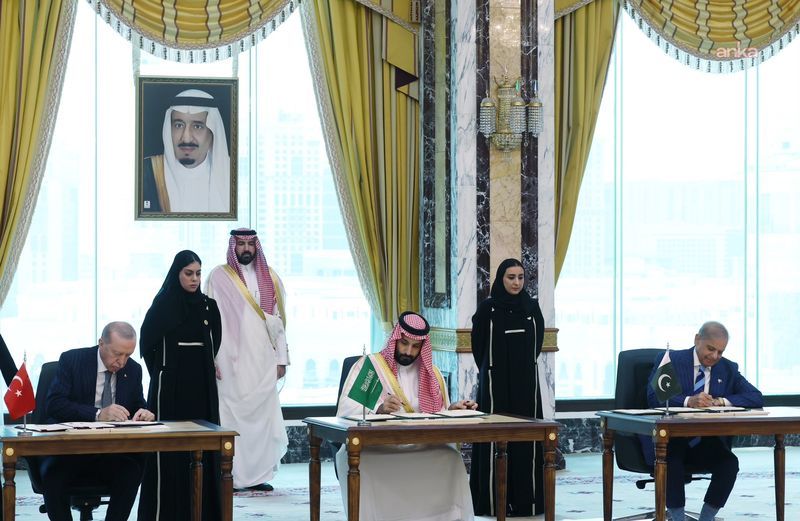 Mekke Ortak Savunma Anlaşması imza töreninde Türkiye, Suudi Arabistan ve Pakistan temsilcileri masalarda belgeleri imzalıyor.