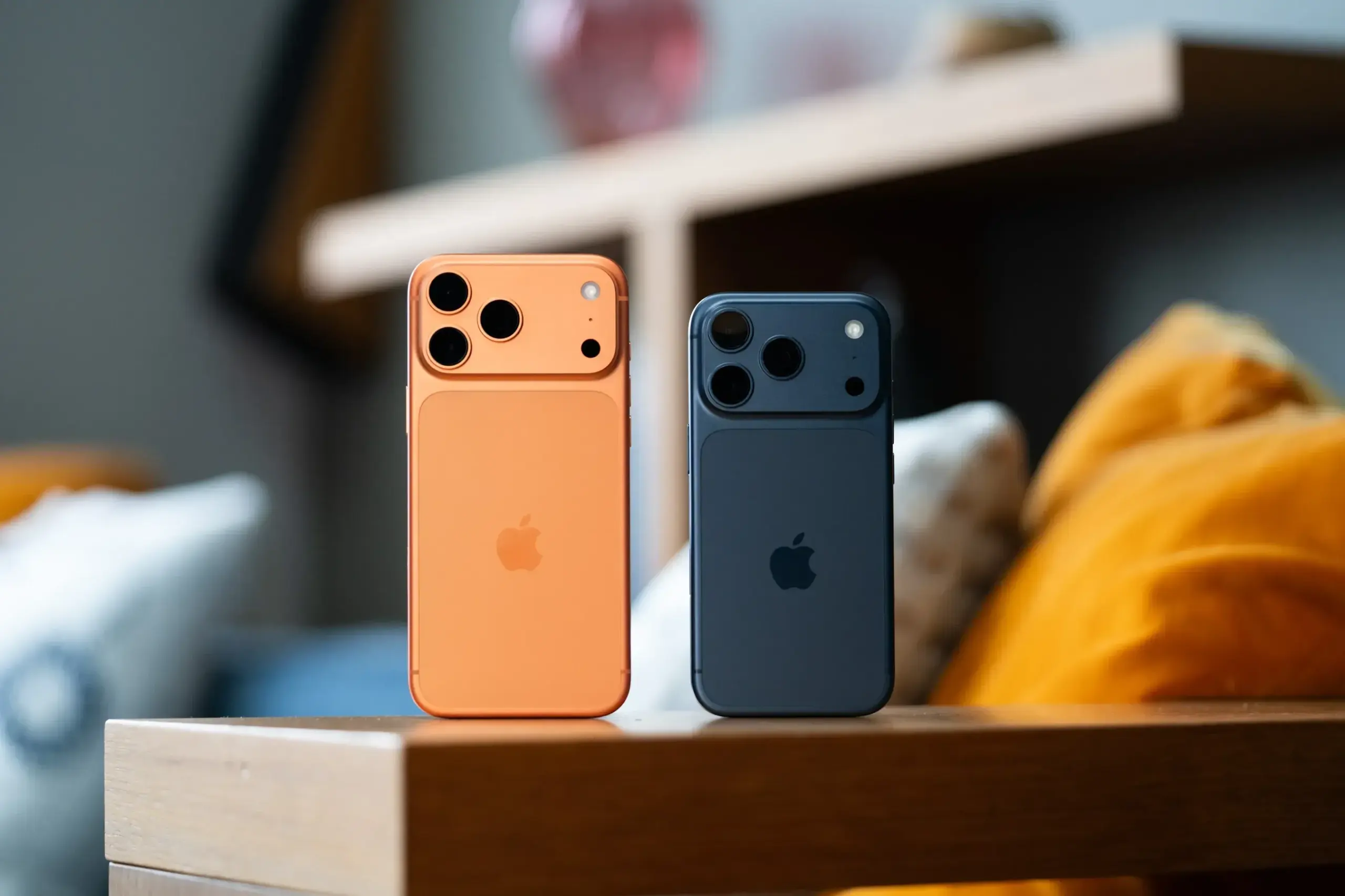 Masa üzerinde duran iki iPhone modelinin arka yüzleri görülüyor.