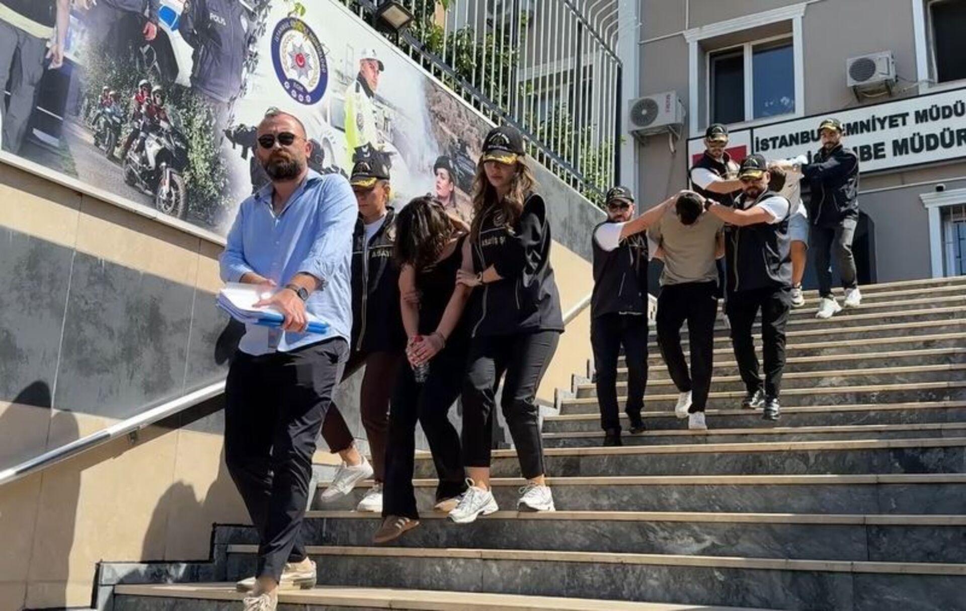 Emniyet binasının merdivenlerinde polis ekipleri eşliğinde çıkarılan şüpheliler.