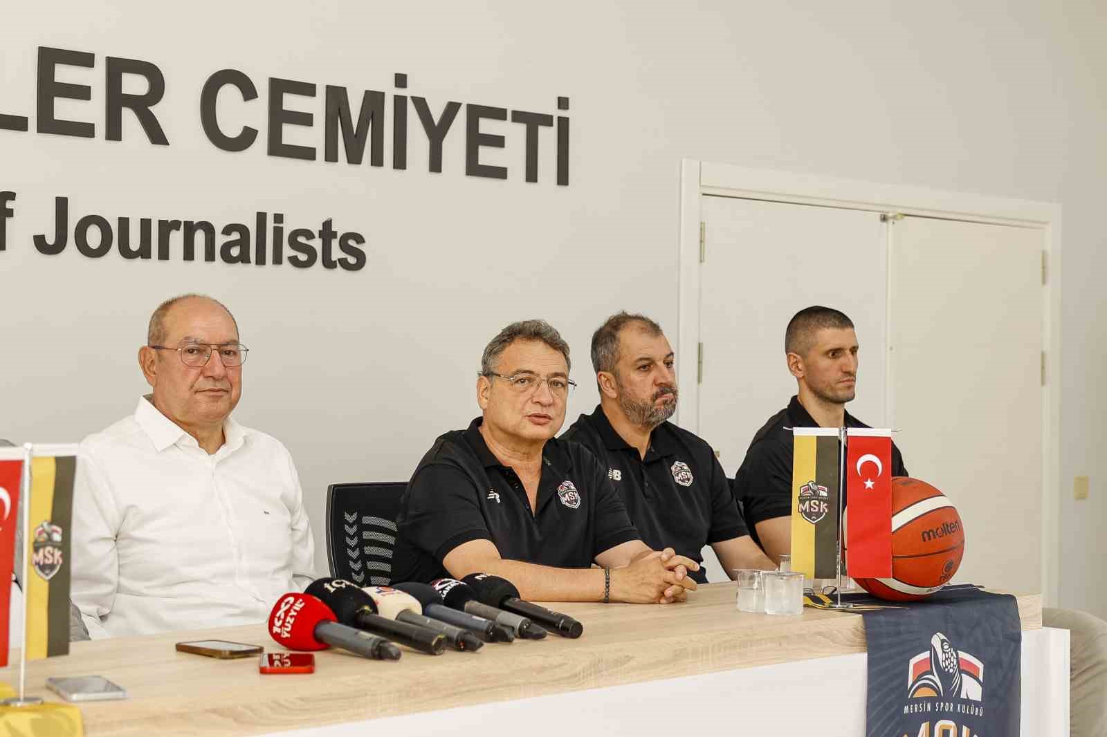 Basın toplantısında masada oturan MSK temsilcileri, mikrofonlar, basketbol topu ve kulüp flamaları görülüyor.