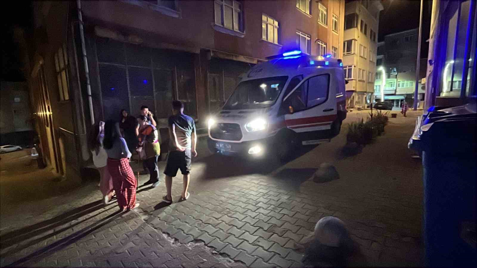 Gece vakti sokakta park halindeki ambulans ve çevrede bekleyen kişiler.