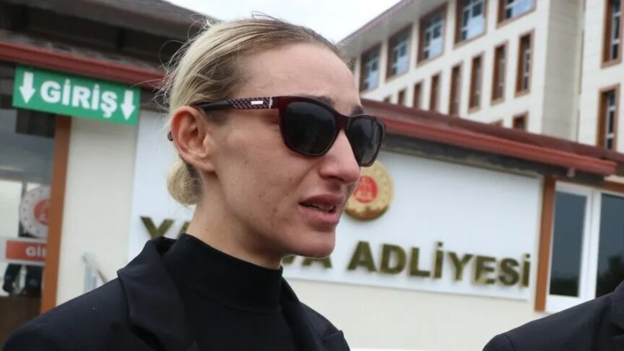 Adliye binası önünde güneş gözlüklü bir kadının görüntüsü.