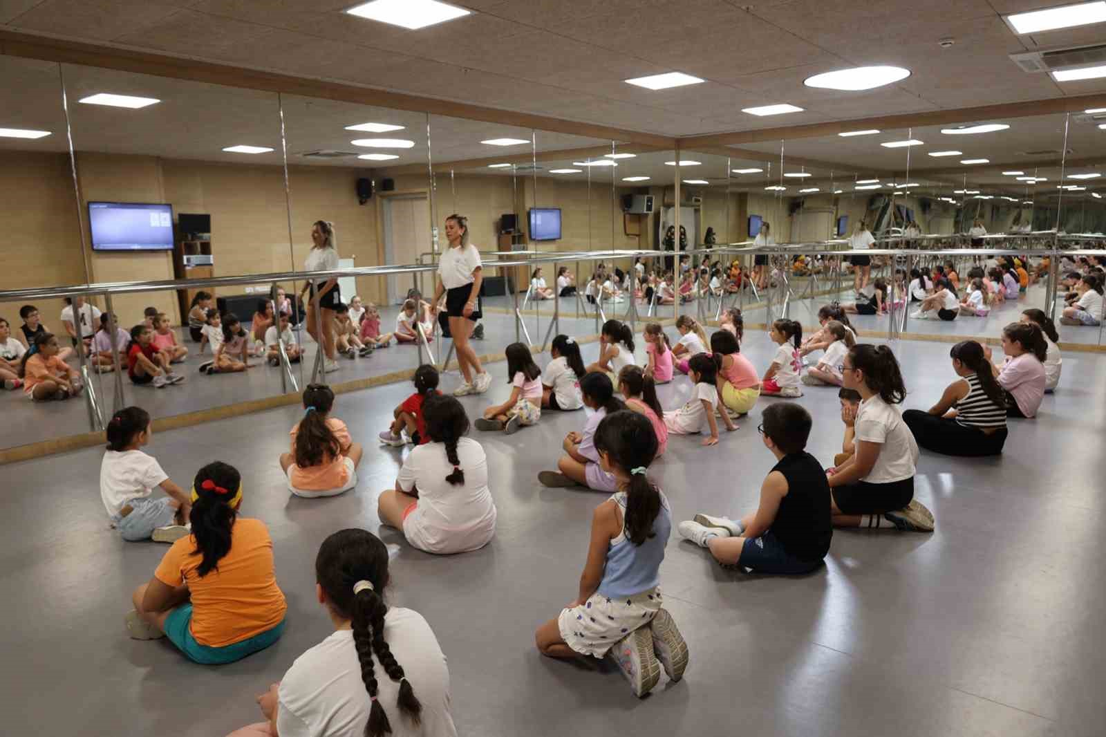 Kapalı spor salonunda eğitmen eşliğinde ders yapan çocuklar.