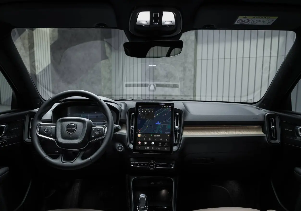 The steering wheel, digital instrument cluster, and large touchscreen on the center console are visible in the Volvo cabin.