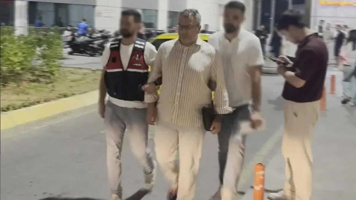 An image of a person walking in front of a building accompanied by officials.
