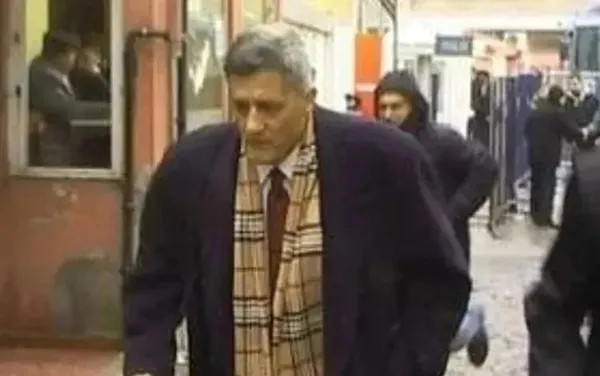 Archive footage of Kaşif Kozinoğlu walking in a building corridor.