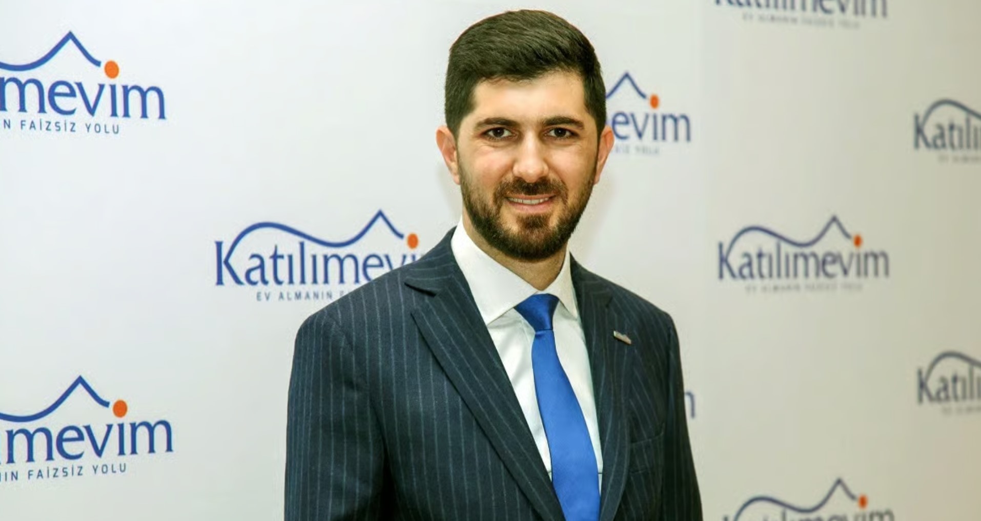 Katılımevim logosunun yer aldığı bir arka plan önünde takım elbiseli bir yönetici portresi.