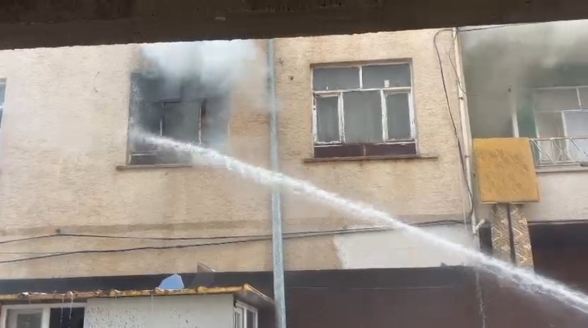 İtfaiye müdahalesi sırasında yangın çıkan dairenin penceresine sıkılan su ve binadan yükselen duman.