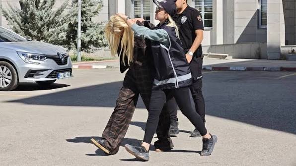 Polis ekipleri tarafından götürülen bir kadın dış mekânda görüntüleniyor.
