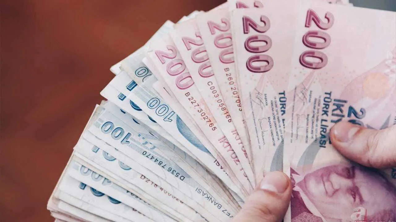 Elde tutulan 100 ve 200 TL'lik banknotların yakın plan görüntüsü.