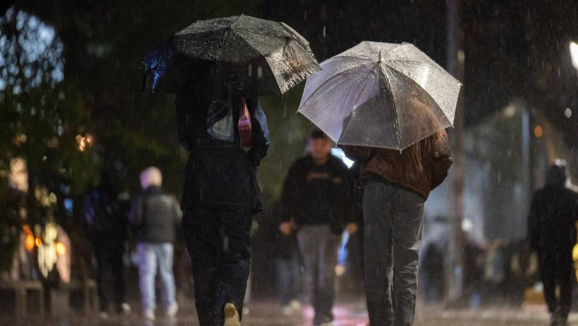 People walking with umbrellas in the night rain.
