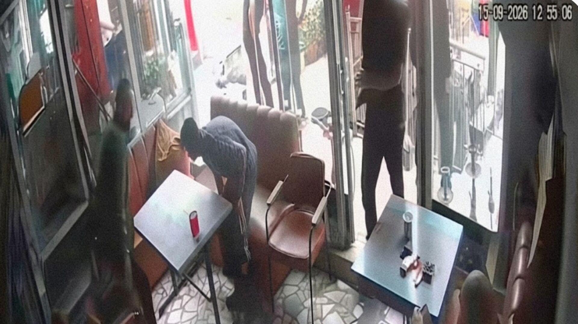 Çay ocağı girişinde ve masaların yanında bulunan kişilerin yer aldığı güvenlik kamerası görüntüsü.