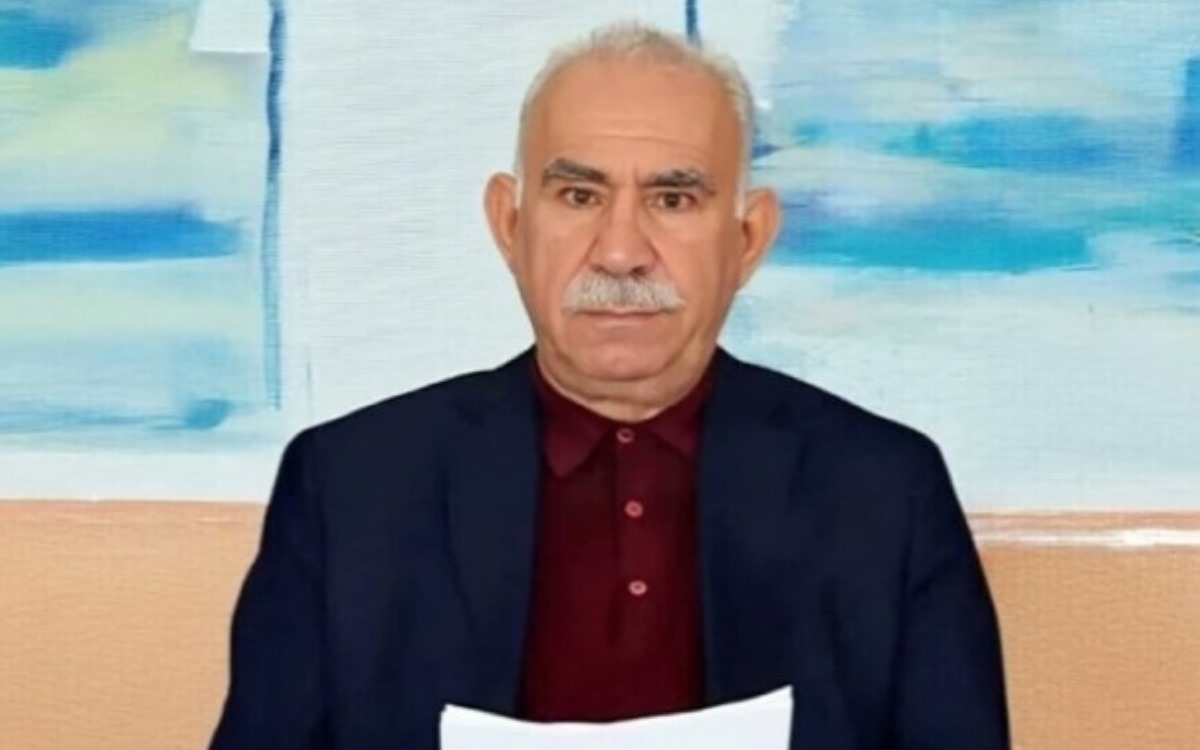 Ein Bild, auf dem Abdullah Öcalan mit einem Papier in der Hand zu sehen ist.