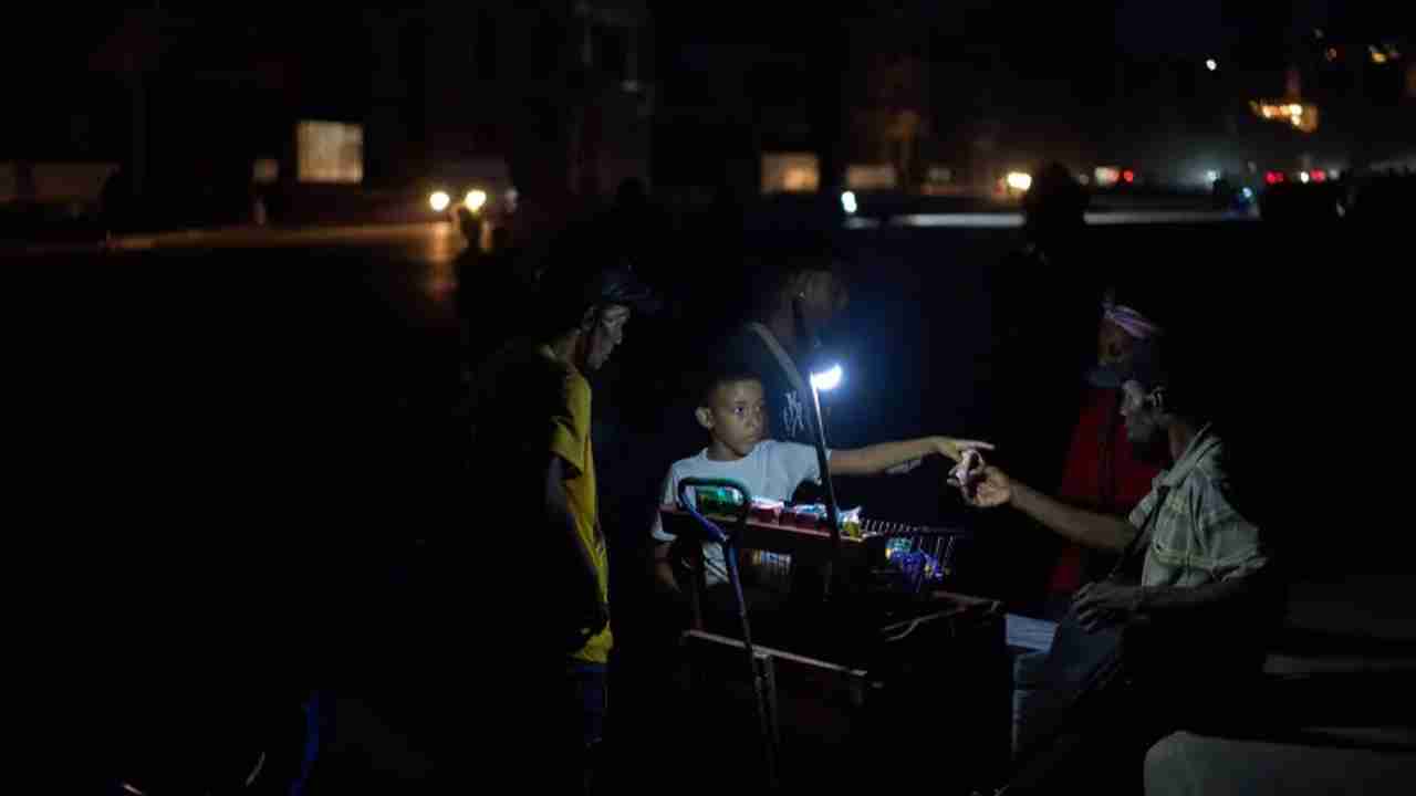 People gathered around a small light source in the dark.