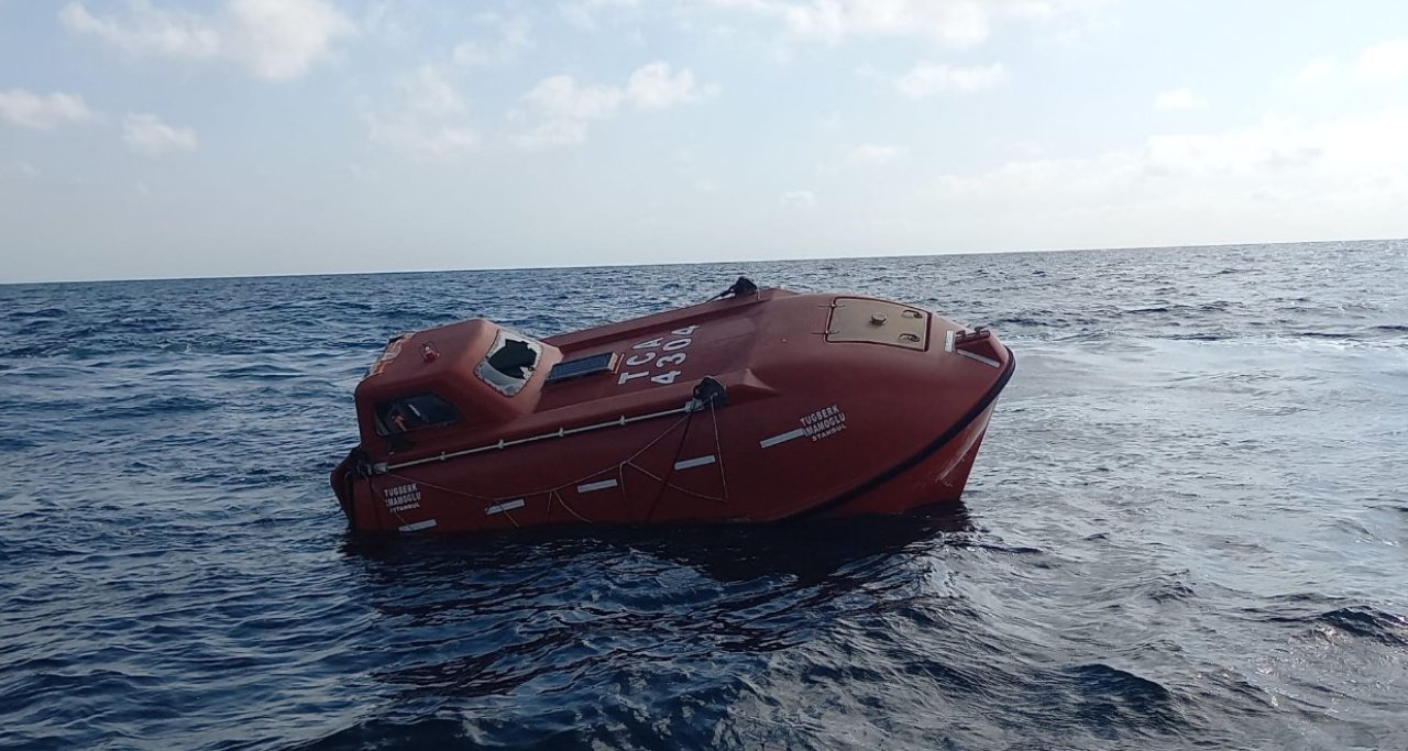 A red-orange lifeboat floating empty on the Sea of Marmara during the day.